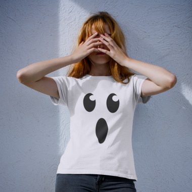 girl wearing a halloween tshirt mockup while covering her face against a white wall a17105