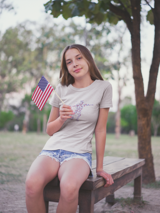 teen girl waving a little american flag wearing a t shirt mockup at the park a20710